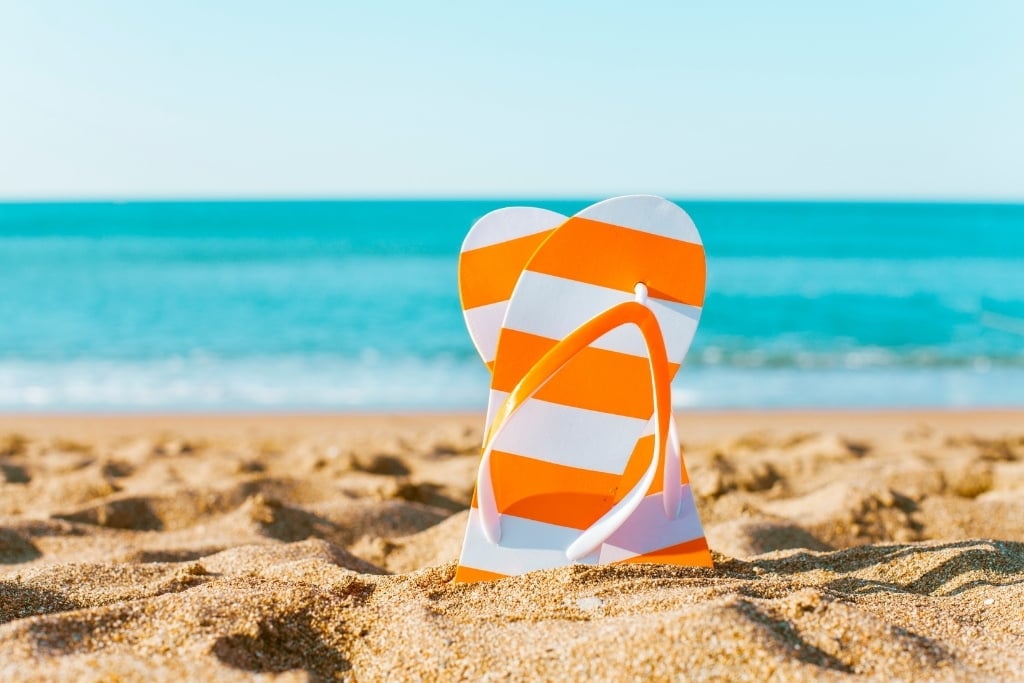 Things You Need To Do Before Your Next Beach Vacation hero flipflops on the beach