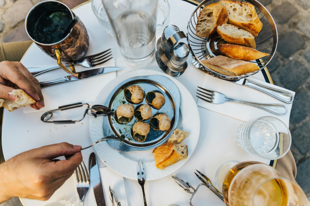 hands reaching for escargot dish on a table